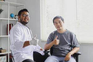 médecin souriant et patient assis côte à côte avec le geste du pouce levé tout en regardant la caméra photo