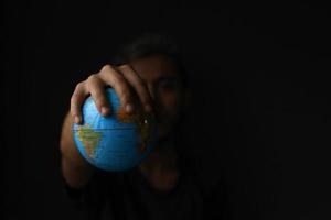 main tenant un globe sur fond noir avec espace de copie. concept du jour de la terre avec photo à faible tonalité