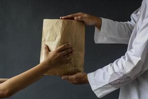 vue latérale des mains musulmanes partageant des sacs d'aumône de riz isolés sur fond noir. photo