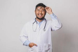 Happy male doctor with smiling face soulevant ses lunettes isolé sur fond blanc photo