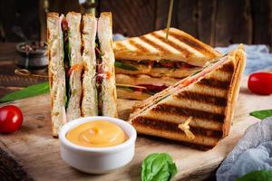 club sandwich avec jambon, tomate, fromage et épinards. panini grillé photo