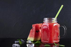 Délicieux smoothie frais à la pastèque avec de la glace sur fond sombre photo