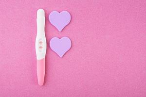 test de grossesse positif avec des coeurs isolés sur fond rose photo