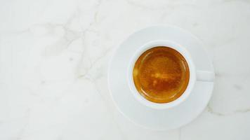 vue de dessus du café expresso chaud dans une tasse blanche sur une table en marbre blanc photo