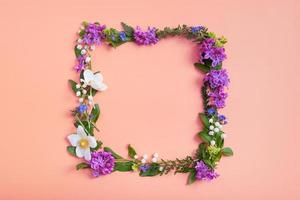 composition d'été ou de printemps sur fond orangr. fleurs violettes, anémone et feuilles vertes avec vue de dessus de couronne d'espace de copie. été, concept floral de printemps photo