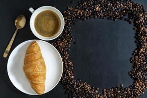 petit-déjeuner café et croissant dans une assiette sur une table en bois.