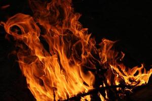 flammes de feu sur fond noir. le feu dans la forêt naturelle, les flammes et les étincelles sur un carburant de fond sombre, les lumières sur fond noir. photo