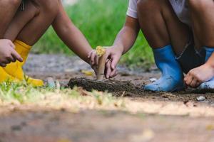 de jolies petites soeurs en bottes utilisent des pelles d'outils de jardin pour planter des plantes dans le jardin. un enfant aide maman dans le jardin, un petit jardinier.
