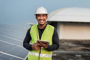 homme ingénieur vérifiant l'énergie des panneaux solaires avec tablette. technicien vérification et services de panneaux solaires photovoltaïques. concept d'énergie durable. photo