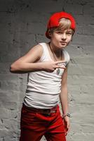 portrait de cool jeune garçon hip hop en chapeau rouge et pantalon rouge et chemise blanche dans le loft photo