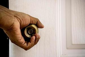 la main tient le bouton de la porte pour ouvrir la porte. photo