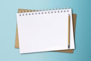 un cahier blanc et un crayon sont placés sur une surface de papier bleu. photo