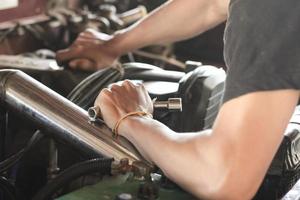 la main d'un homme qui répare le moteur d'une voiture cassée photo