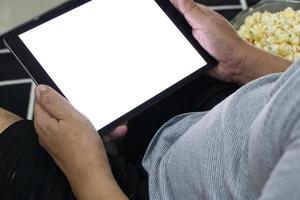 tasse en verre avec tablette numérique de pop-corn salé dans un fauteuil gris. photo