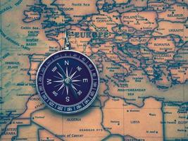 la boussole est placée sur la carte du monde antique ou vintage entre le continent européen et le continent africain. fond de concept de navigation géographie voyage. photo