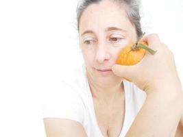 Quarante neuf ans femme dans un t-shirt blanc sur un fond blanc avec une orange photo