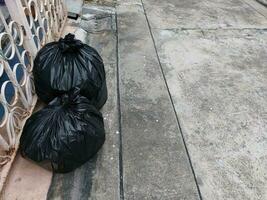 deux sacs poubelles noirs ont été placés du côté gauche de la clôture sur la route du village. photo