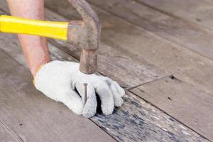 main d'un homme dans un sac tenant des clous sur un plancher en bois photo