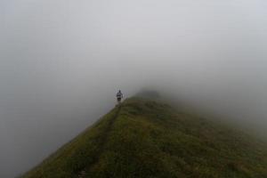 compétition de course de montagne extrême skymarathon. coureur sur un sentier de crête vers le brouillard photo