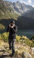 photographe de jeune homme prenant des photos avec un appareil photo numérique dans une montagne.