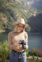 photographe touriste voyageur debout sur le dessus vert sur la montagne tenant dans les mains un appareil photo numérique