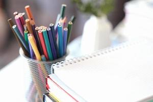 retour à l'école 2022, crayons de couleur. vue recadrée d'une pile de livres et d'un cahier ou d'un bloc-notes photo