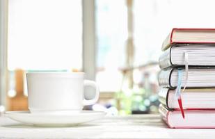 tasse de café classique blanche sur une table blanche sur la terrasse et une pile de livres avec des signets. apprentissage de la lecture et étude, heures du matin pour l'auto-éducation photo