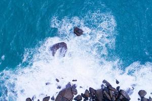 vue aérienne de haut en bas bord de mer grande vague se brisant sur une falaise rocheuse belle surface de la mer sombre en journée ensoleillée fond d'été paysage marin incroyable vue de dessus bord de mer à phuket en thaïlande photo