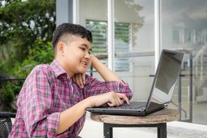 les garçons asiatiques aiment étudier en ligne devant chez eux pendant les vacances scolaires. photo