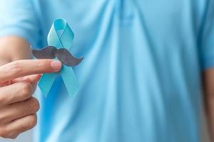 novembre mois de sensibilisation au cancer de la prostate, homme tenant un ruban bleu avec moustache pour soutenir les personnes vivant et malades. soins de santé, hommes internationaux, père et concept de la journée mondiale du cancer photo