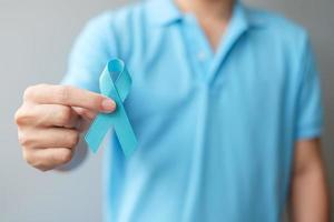 novembre mois de sensibilisation au cancer de la prostate, homme en chemise bleue avec la main tenant un ruban bleu pour soutenir les personnes vivant et malades. soins de santé, hommes internationaux, père et concept de la journée mondiale du cancer photo