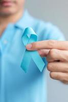 novembre mois de sensibilisation au cancer de la prostate, homme en chemise bleue avec la main tenant un ruban bleu pour soutenir les personnes vivant et malades. soins de santé, hommes internationaux, père et concept de la journée mondiale du cancer photo