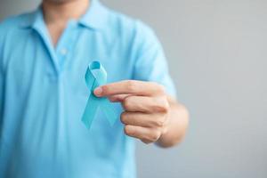 novembre mois de sensibilisation au cancer de la prostate, homme en chemise bleue avec la main tenant un ruban bleu pour soutenir les personnes vivant et malades. soins de santé, hommes internationaux, père et concept de la journée mondiale du cancer photo