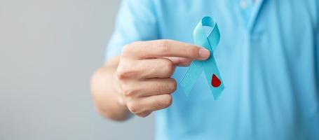 novembre mois de sensibilisation à la journée mondiale du diabète, homme tenant un ruban bleu clair en forme de goutte de sang pour soutenir les personnes vivant, la prévention et la maladie. soins de santé, concept de la journée du cancer de la prostate photo