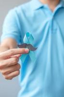 novembre mois de sensibilisation au cancer de la prostate, homme tenant un ruban bleu avec moustache pour soutenir les personnes vivant et malades. soins de santé, hommes internationaux, père et concept de la journée mondiale du cancer photo