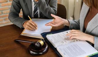 des hommes d'affaires et des avocats discutant des documents contractuels assis à la table. notions de droit, conseils, services juridiques. photo