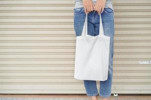 femme hipster tenant un sac fourre-tout blanc pour maquette modèle vierge photo