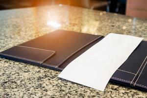 Livre blanc vide vide dans le dossier de reçu de facturation de paiement de restaurant sur la table de granit photo