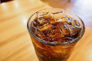 verre de cola avec de la glace sur une table en bois en arrière-plan du restaurant photo