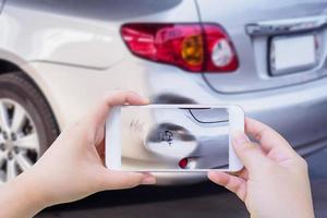 femme utilisant un smartphone mobile prenant une photo d'un accident de voiture endommagé pour l'assurance