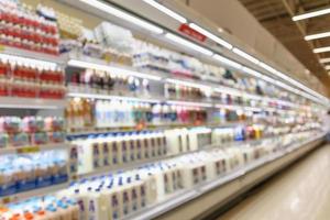 étagères de réfrigérateur de supermarché flou abstrait avec des bouteilles de lait et des produits laitiers photo
