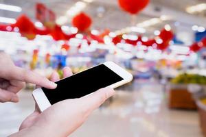 femme utilisant un smartphone mobile lors de ses achats dans un supermarché photo