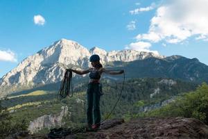 une femme dans un casque enroule une corde dans le contexte d'une grande montagne photo