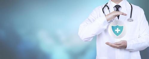 concept de protection de la santé des patients. le médecin montre un bouclier protecteur avec une croix sur fond bleu. photo