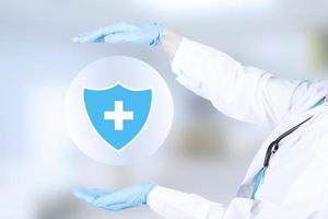 concept de protection de la santé des patients. le médecin montre un bouclier protecteur avec une croix sur fond bleu. photo