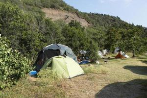 camping et tente touristique sur une côte sauvage au bord de la mer, tôt le matin contre un ciel bleu avec des nuages. photo