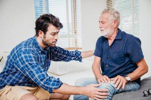 jeunes hommes soins de santé oncle âgé à la maison, vieil homme douleur à la jambe du genou. photo