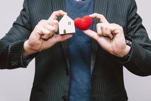 l'homme d'affaires s'occupe de la maison et du coeur rouge pour rester à la maison ou aimer les gens dans le concept de famille de la maison. photo