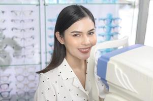 jeune cliente en cours d'examen test visuel à l'aide d'un autoréfracteur par un ophtalmologiste dans un centre optique, concept de soins oculaires. photo