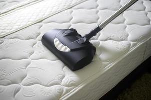 les nettoyeurs de maison utilisent une machine anti-acariens dans le lit. photo